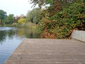 Holzterrasse am Ufer, Granitsitzblock, natürliche Uferbepflanzung