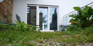 Blick von extensiver Dachbegrünung mit Kies sedum, Hosta auf Sitzpatz mit Spalier, Liegestühlen und Terrassenfensterfront