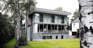 Blick auf Villa mit Terrasse, Terrassentreppe, Trittplatten im Rasen, Hecke und Birken