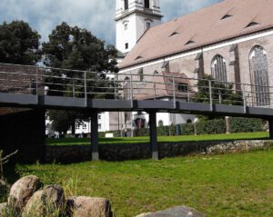 barrierefreie Erschließung über Metallsteg auf Wiese vor Denkmalgeschützter Kirche in Fürstenwalde